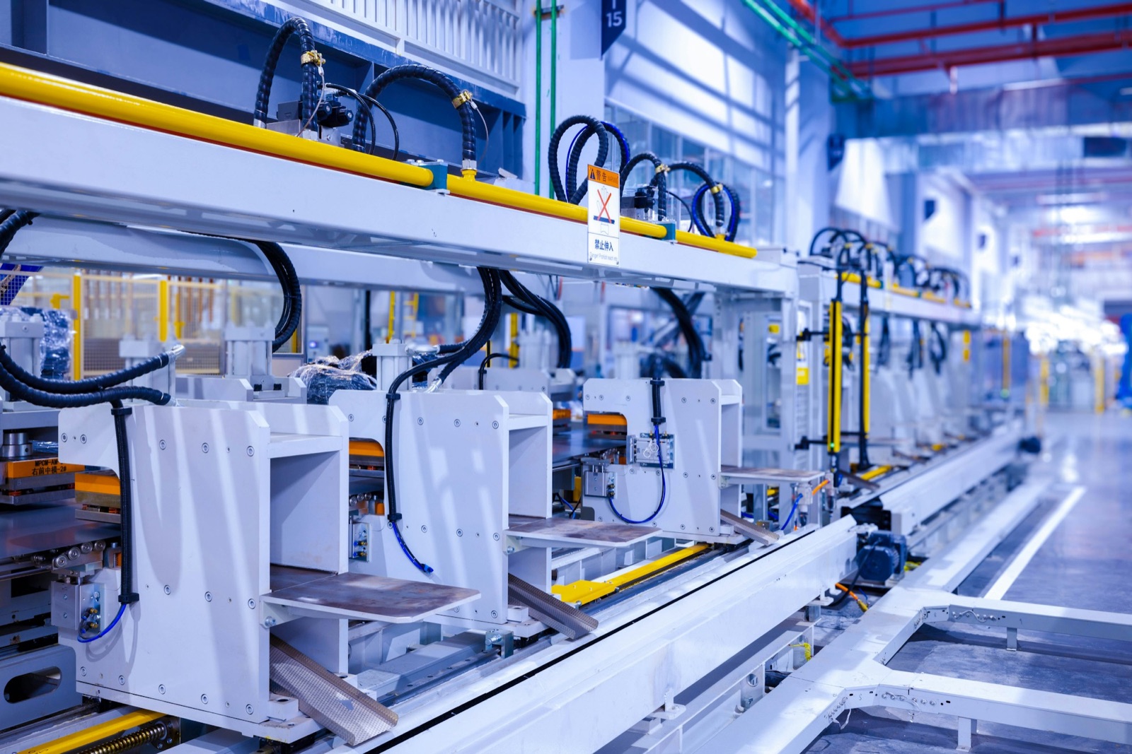 Automated assembly line with stamping stations and conveyor rails in a factory hall