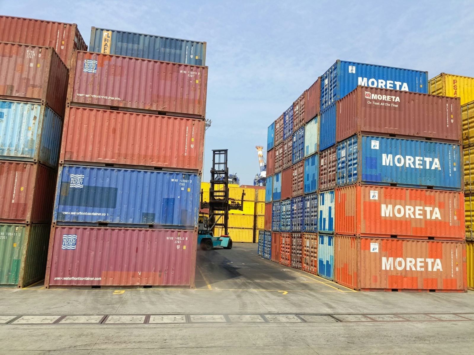 Stacked shipping containers in a port yard with a container handler